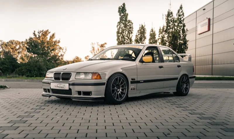 Tiefergelegter BMW 3er E36 mit Frontspoiler und schwarzen Felgen im Abendlicht