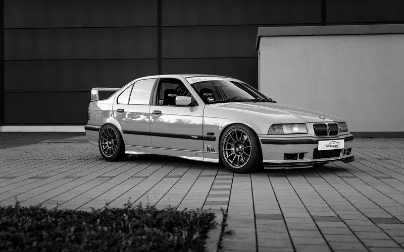 BMW 3er E36 mit Heckflügel und Schalensitzen in Seitenansicht, Schwarz-Weiß-Aufnahme