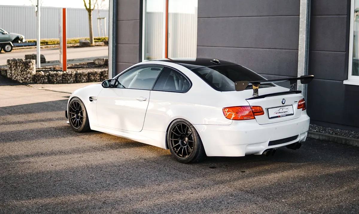 Weißer BMW M3 E92 mit Heckflügel und schwarzen Leichtmetallfelgen vor der Werkstatt von 613 Motorsport