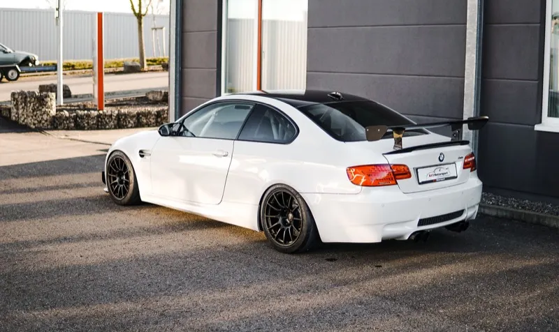 Weißer BMW M3 E92 mit Heckflügel und schwarzen Leichtmetallfelgen vor der Werkstatt von 613 Motorsport