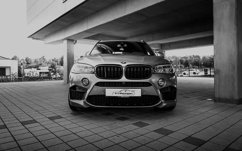 BMW X5 M in Frontansicht mit schwarzer Niere unter einem Parkdeck, Schwarz-Weiß